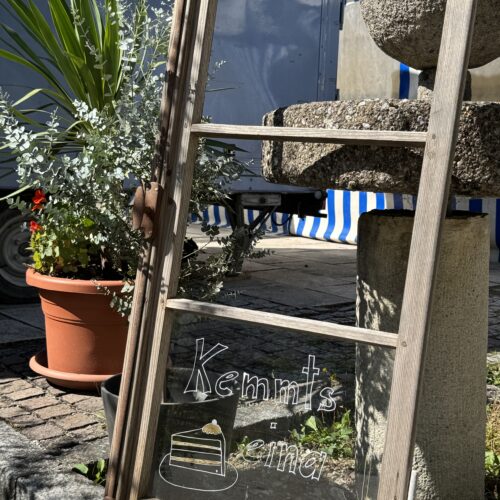 Dekorativer Spiegel mit handgeschriebener Einladung vor dem Café des Lebens