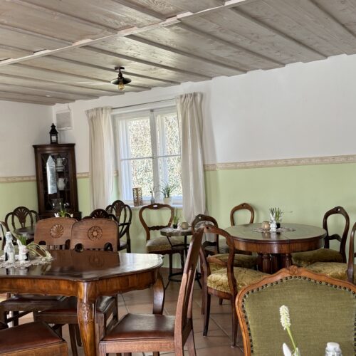 Gemütlicher Gastraum mit Holztischen und klassischen Stühlen im Café