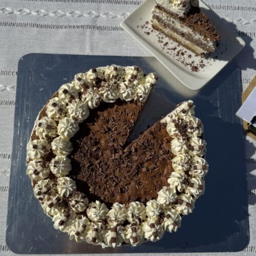 Hausgemachter Schokoladenkuchen mit Sahne dekoriert auf einer Tortenplatte