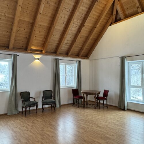 Heller Saal mit Holzboden und Sitzmöglichkeiten im Café des Lebens